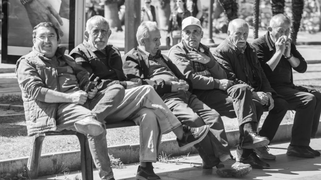 6 ältere Männer sitzen auf einer Bank