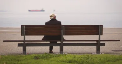Ein Senior sitzt auf einer Bank und schaut aufs Meer