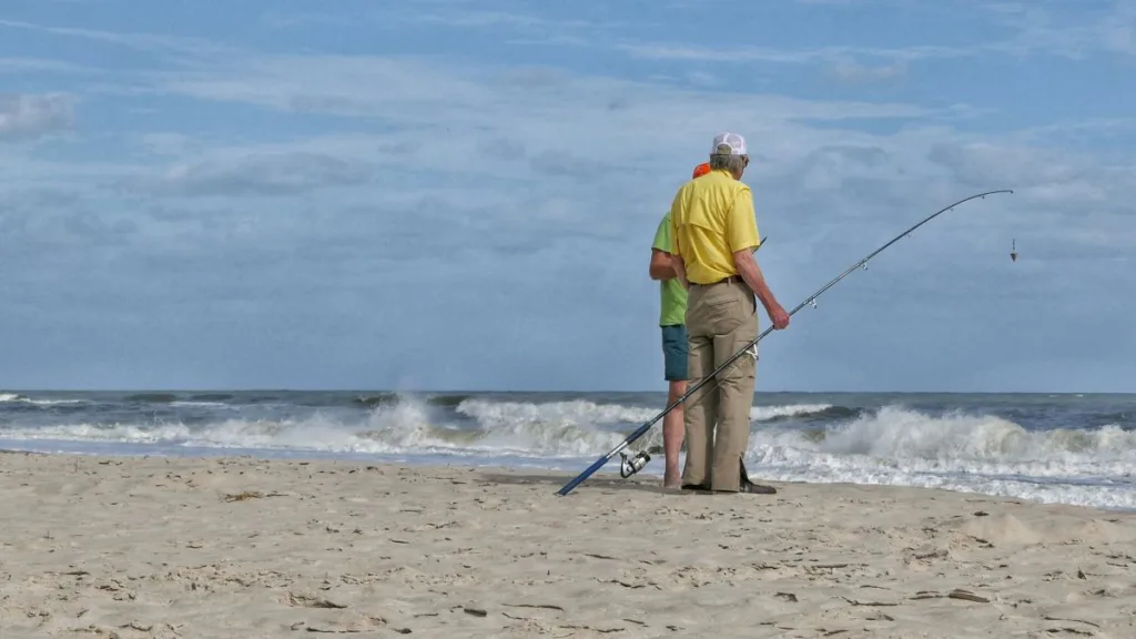 zwei ältere Herren stehen mit einer Angel am Strand