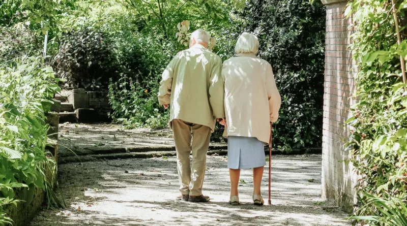 ein älteres Paar geht mit gehstöcken einen Weg entlang
