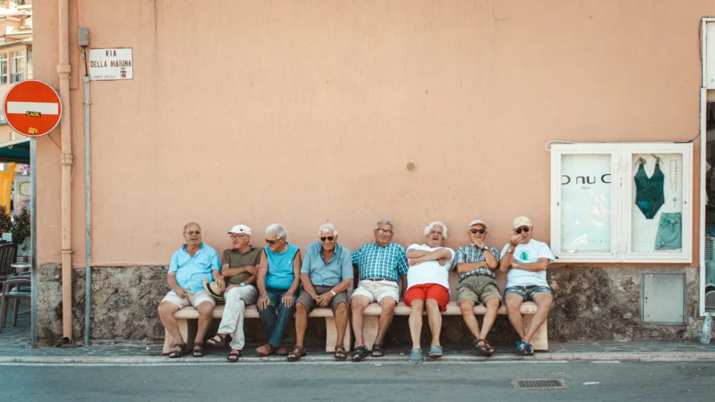 8 Senioren sitzen auf einer Bank in Italien