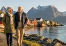 Älteres Paar an einem norwegischen Fjordufer, Blick auf Holzhäuser und Wasser