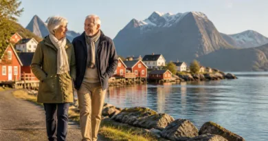 Älteres Paar an einem norwegischen Fjordufer, Blick auf Holzhäuser und Wasser