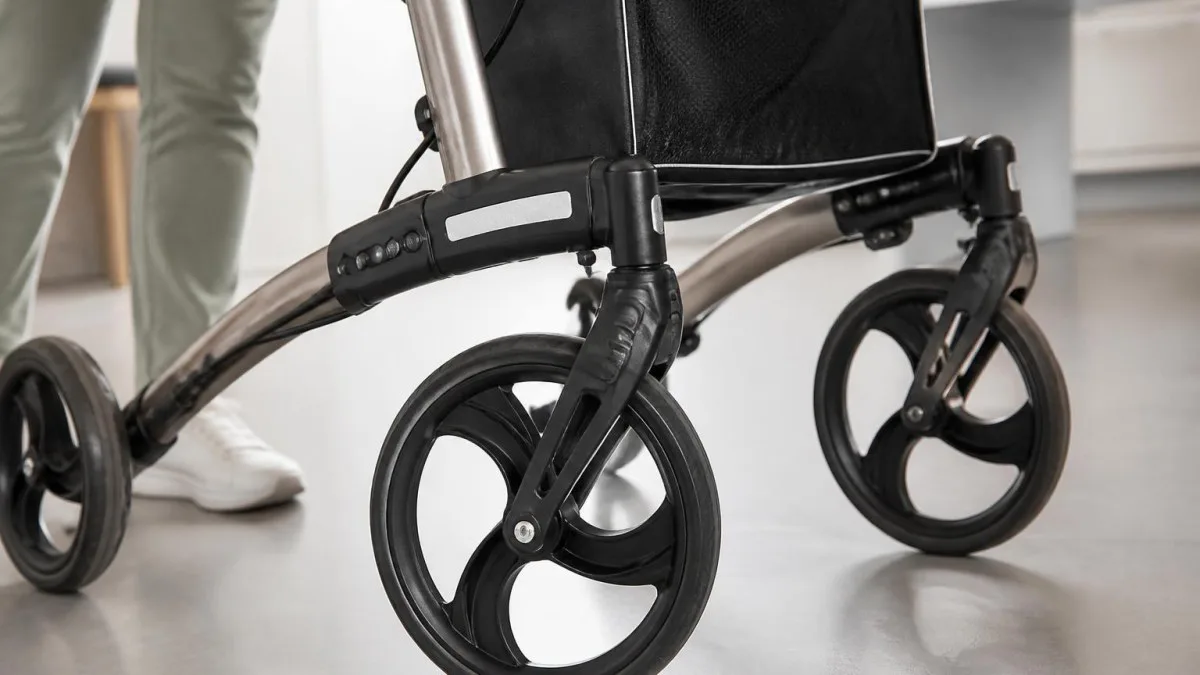 Detailaufnahme von Rolle und Bremse eines Rollators auf Wohnraum-Boden